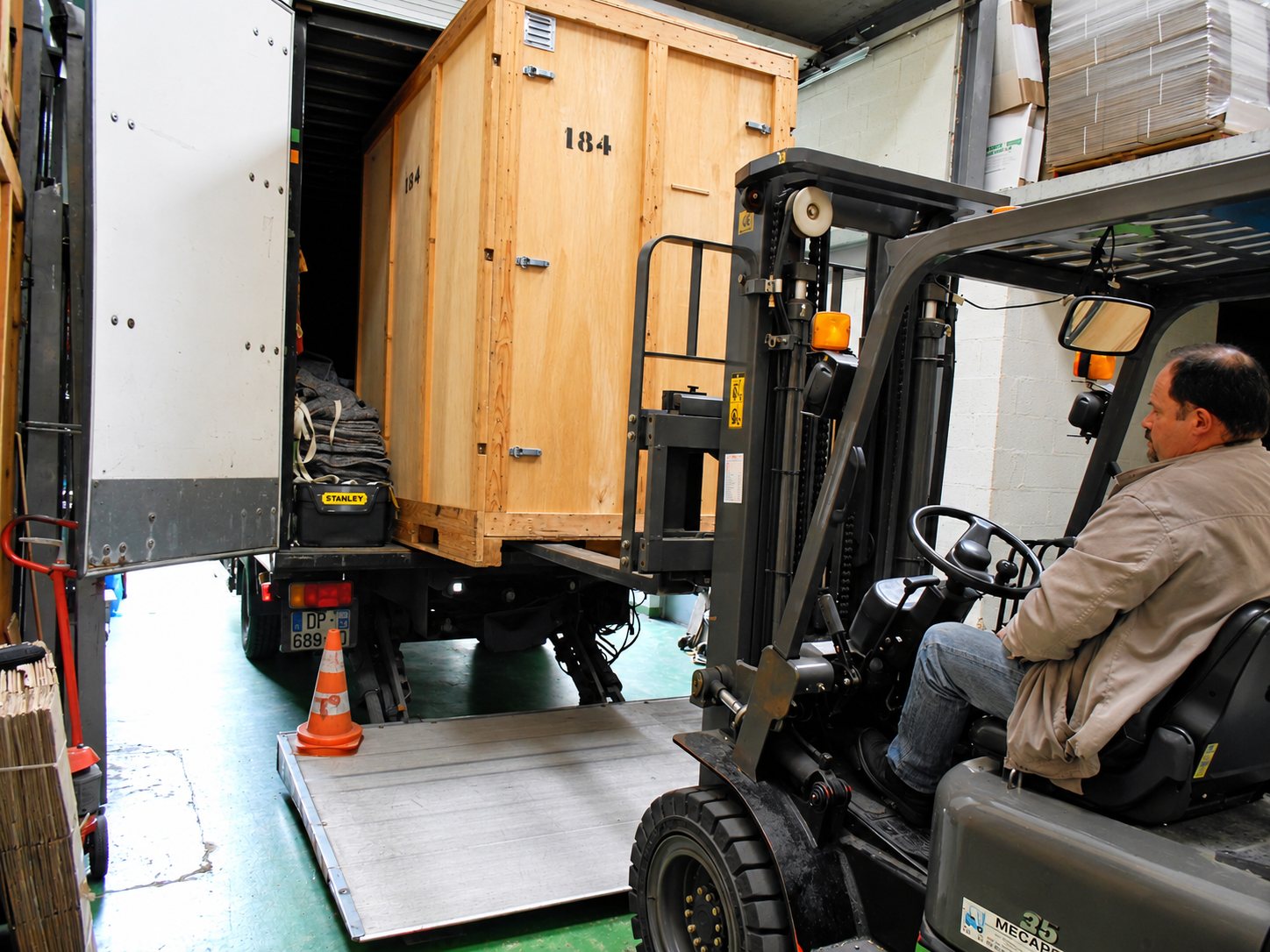 Chargement d'une grande caisse en bois dans un camion avec un chariot élévateur